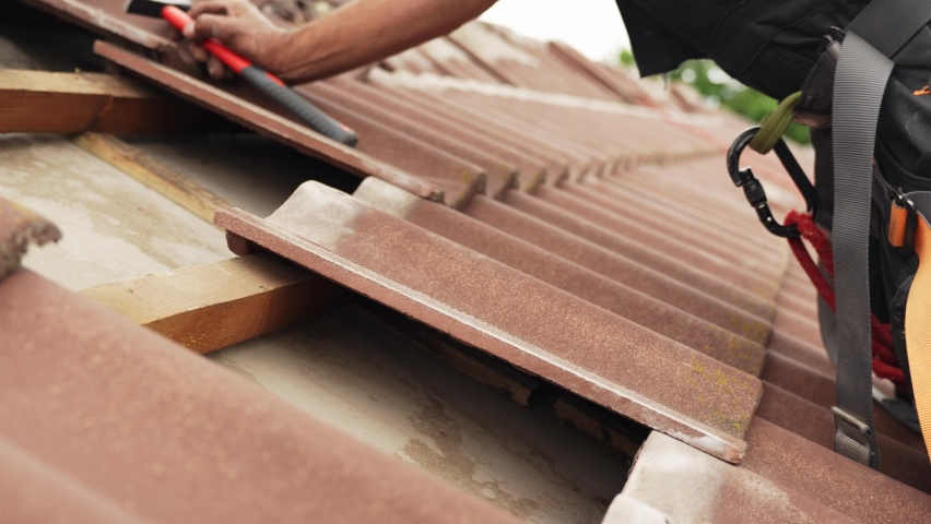Close up of a person carefully putting back roof tiles after adding solar panels mounts | Shutterstock HD Video #1093224493