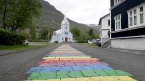 Seydisfjordur, Iceland Blue Church with rainbow sidewalk and gimbal video low walking forward.