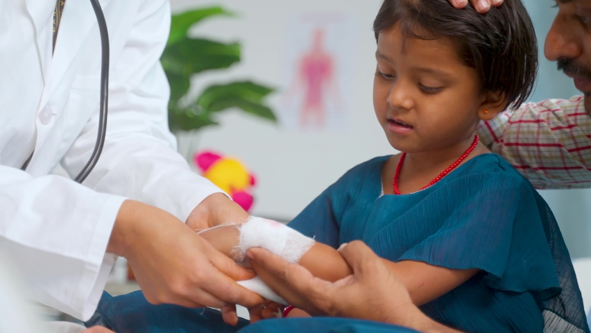 Close up shot Doctor hand tying bandage to worried kids injured hand while with caring father at hospital - concept of medicare, childhood mischief and medical first aid. | Shutterstock HD Video #1093226215
