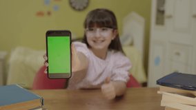 Little cute beautiful girl using new technology while playing online game with smartphone. Girl watches funny videos on her cell phone, shows green screen phone and is surprised by what she sees.