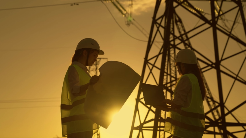 Colleagues discuss plan of work. Teamwork work of power engineers with computer in protective helmets, maintenance of power lines in outdoors. Civil engineers work together using laptop on power line | Shutterstock HD Video #1093237817