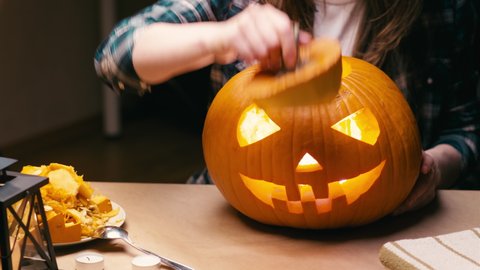 Illuminating pumpkin for Halloween. Woman sitting, lighting and showing out candle lit halloween Jack O Lantern pumpkin at home for her family.: stockvideo