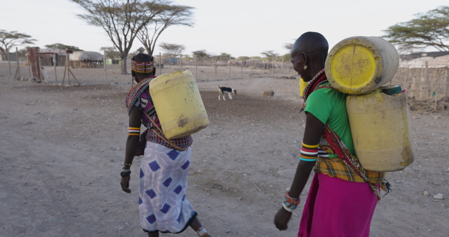 AFRICA,KENYA,CIRCA 2022. Slow motion.Climate change.water crisis.African woman carrying water in plastic containers on their backs they collected from a water point due to persistent drought. Kenya