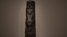 This video shows a large wooden totem pole against a white background.