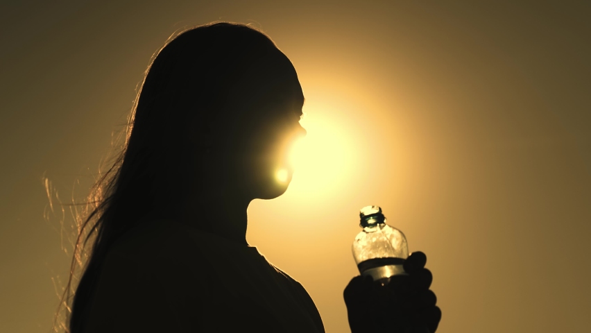 silhouette girl drinking water from bottle glare sun. man quenches thirst sunset. girl wants drink energy drink dawn. sport drinking water. man outdoors drinks water. healthy lifestyle drinking regime Royalty-Free Stock Footage #1093261777