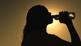 silhouette girl drinking water from bottle glare sun. man quenches thirst sunset. girl wants drink energy drink dawn. sport drinking water. man outdoors drinks water. healthy lifestyle drinking regime - Powered by Shutterstock - Get 15% off with code: PIKWIZARD15