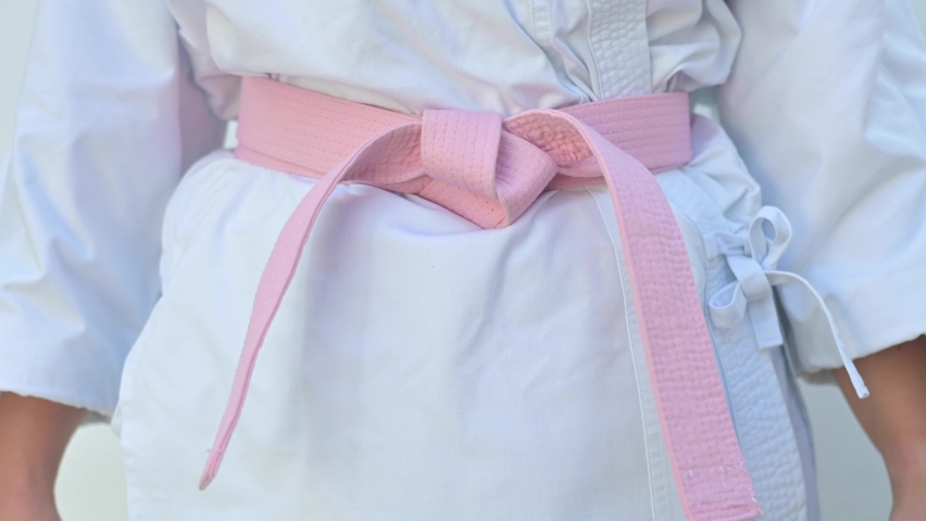 Woman in a pink head covering and karate outfit with a pink belt. Fight against cancer concept.