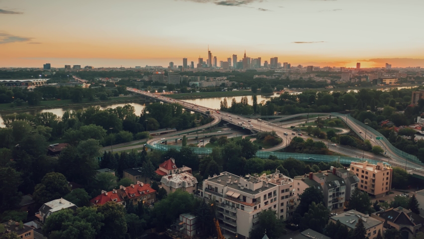 Stunning sunset, aerial view of Warsaw, Poland. Drone time-lapse, hyperlapse. Flyover modern city skyline, downtown business center skyscrapers, highway driving cars. Cloudscape evening dusk