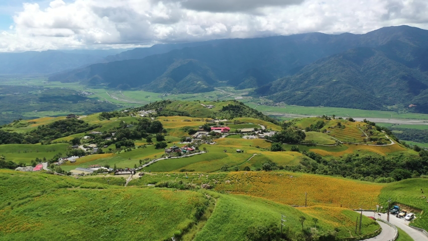 Aerial view of a drone above Liushidan Mountain, with country roads winding thru daylily flower farms on the hills, which overlook the East Rift Valley on a sunny summer day, in Fuli, Hualien, Taiwan