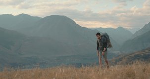 A young man is walking uphill with a beautiful mountain landscape on his way to the goal. Video photostock in search of new ideas. The concept of an interesting life and adventure.
