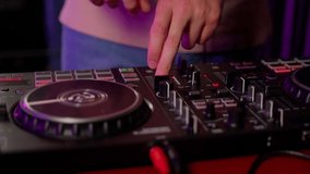Close up DJ using controller console to mix music list in club. Caucasian deejay person touch control panel for change audio on disco party indoors. Slow motion video with movement