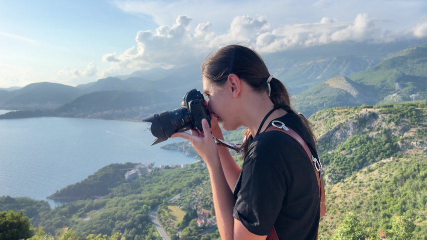 Girl photographer takes pictures against the backdrop of mountains and the sea