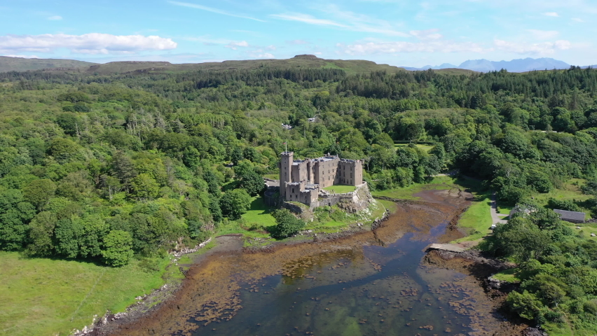 Dunvegan Castle, captured by drone in a smooth, sweeping shot around the castle, showing the stunning scenery surrounding the castle as well as the magnificent grounds.