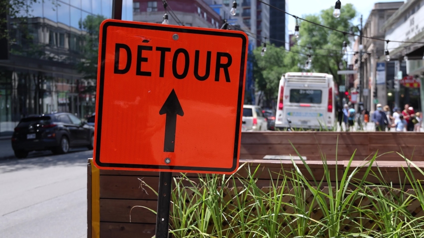 Closeup slow mo video of an orange detour sign on a busy road in Montreal, Canada. City center traffic is seen queuing in background with copy space. Royalty-Free Stock Footage #1093283767