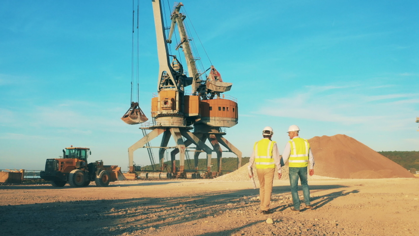 Quarry zone with mechanical loaders and two engineers talking