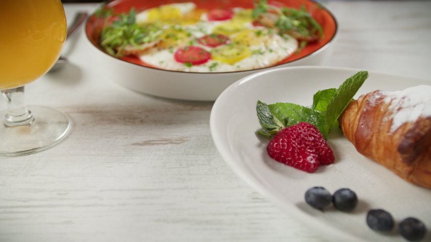 the girl eats scrambled eggs with tomatoes and herbs for breakfast
