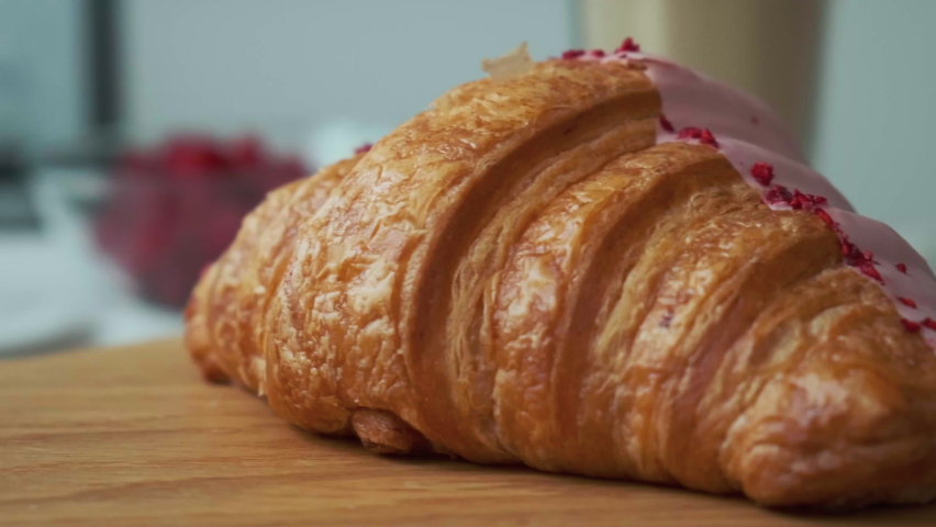 women's hands cut a croissant with raspberry, strawberry cream