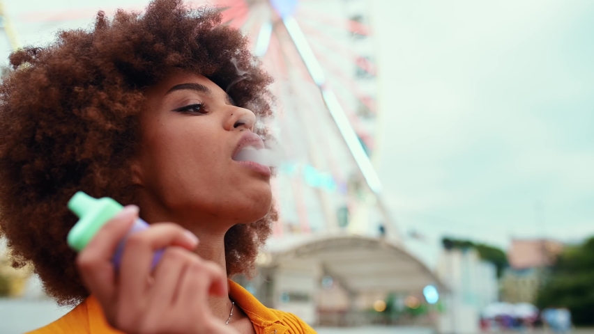Beautiful young woman vaping with an electronic cigarette and having fun blowing the dense smoke out | Shutterstock HD Video #1093313969