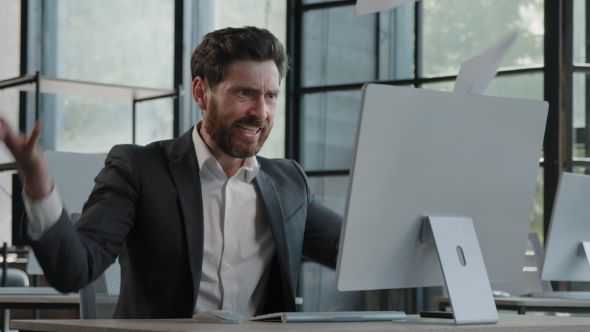 Adult bearded Caucasian angry businessman tired unhappy mad man sit at desk feel stress with paperwork deadline upset trouble with work throwing papers hate job nerves difficult startup worry Royalty-Free Stock Footage #1093323957