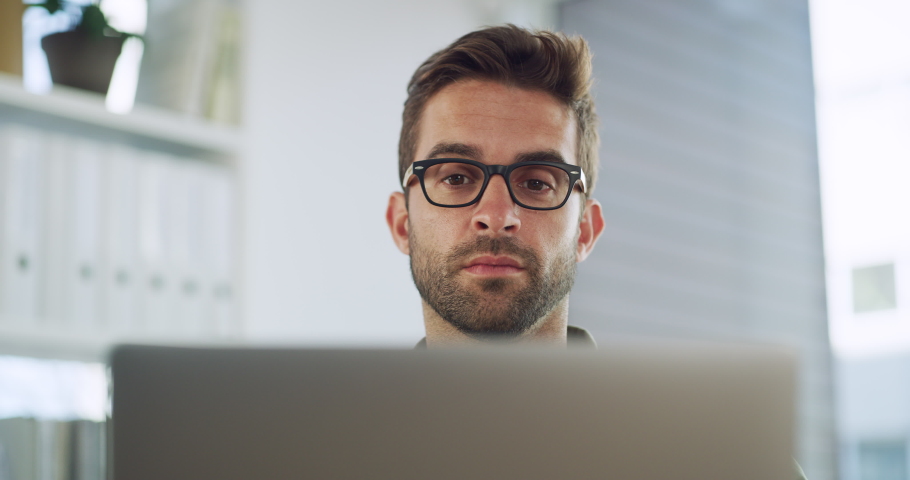 Small business owner or startup entrepreneur working on his laptop, remote from home in his office or study. Business man wearing glasses typing and sending email communication while smiling Royalty-Free Stock Footage #1093328177