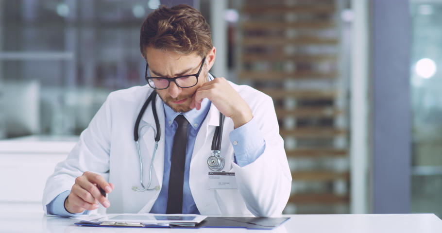 Serious, concerned and confused medical healthcare doctor revising a patients records on a tablet. A professional surgeon is unsure about a report going through test results of a client. Royalty-Free Stock Footage #1093328203