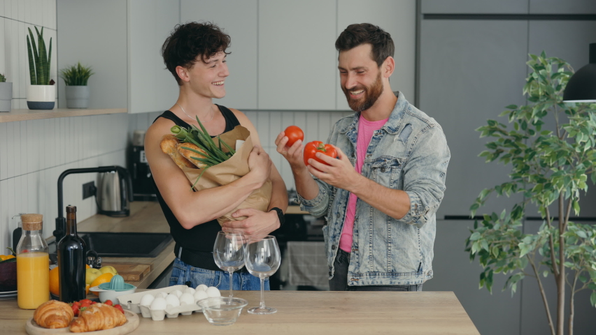 Loving male lgbt couple came from the grocery store to home with shopping and one partner is unpacking the products. People and relationship concept