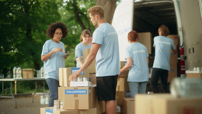 Group of Hardworking Volunteers Preparing Donated Free Food Rations, Loading Packages in a Cargo Van on a Sunny Day. Charity Workers Work in Local Humanitarian Aid Organization. Royalty-Free Stock Footage #1093336553