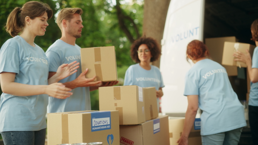 Positive Group of Hardworking Volunteers Preparing Donated Free Food Rations, Loading Packages in a Cargo Van on a Sunny Day. Charity Workers Work in Local Humanitarian Aid Organization. Royalty-Free Stock Footage #1093336561