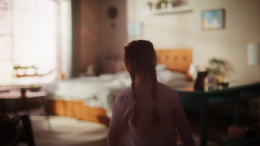 Adorable Little Girl Having Fun at Home, Running Around and Jumping on a Bed in Stylish Bedroom in Loft Apartment. Happy Child Enjoying Childhood and Playing at Home. Slow Motion Footage.