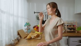 Asian young attractive woman drink a glass of water in kitchen at home. Young thirsty beautiful girl holding clean mineral natural in cup after wake up and sipping in morning for health care in house. - Powered by Shutterstock - Get 15% off with code: PIKWIZARD15