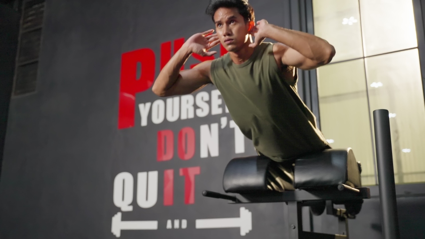 Asian handsome sportsmale working out on equipments in fitness club. Attractive young athlete man doing abs workout and excercise to building muscle for health care and wellness in gymnasium stadium.
