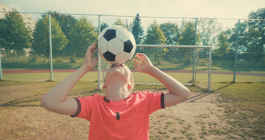Boy football players in dynamic action have fun playing football in the grass, summer sunny day under sunlight.