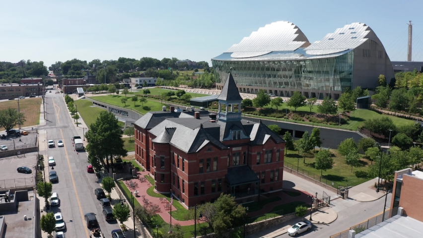 Descending close-up aerial shot of a historic 19th century brick building with the contemporary Kauffman Center for the Performing Arts glass building in the background in Kansas City, Missouri. 4K