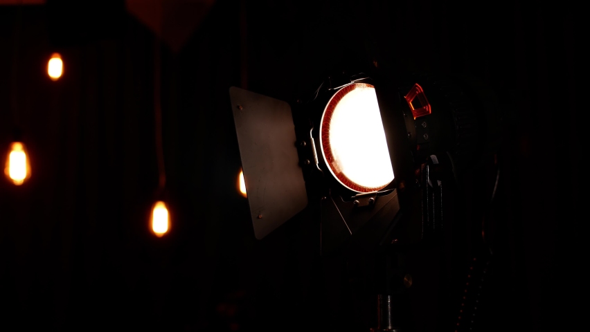 the lighting device in the video studio is set to work the man walks away and turns the beam of light past the camera lens, which creates beautiful curls Royalty-Free Stock Footage #1093343047