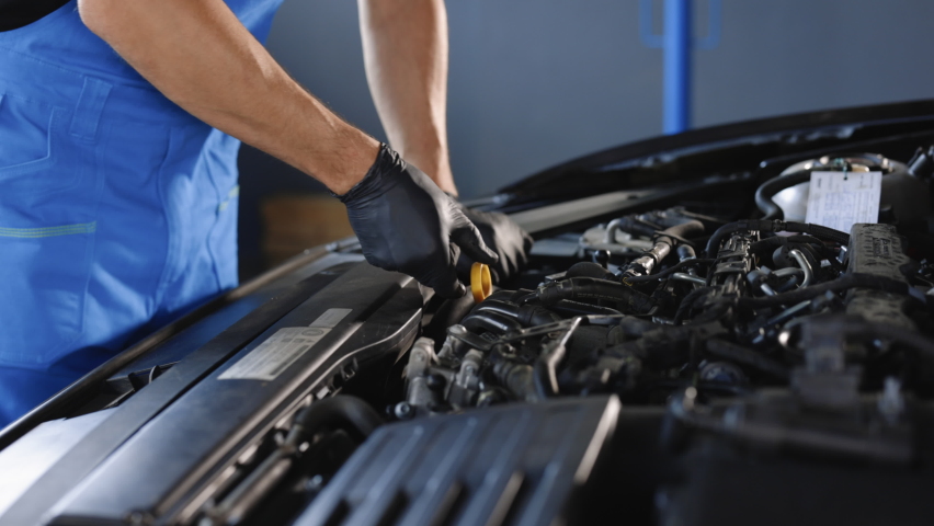 Close-up of automotive mechanic checks the oil level on the car engine dipstick. Car oil quality. Inspection of the engine and checking motor oil level. Man checks the car oil level with dipstick. Royalty-Free Stock Footage #1093345991