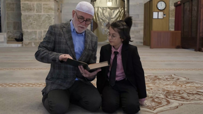 Little boy and his grandfather taking Qur