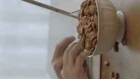 A freelance man drinks coffee, eats roasted almonds, hazelnuts, cookies while working remotely from his home. Close-up portrait of man's hands eating roasted almonds or hazelnuts.Vertical video.