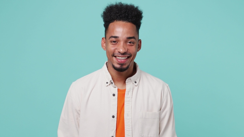Young cheerful fun satisfied man of African American ethnicity 20s he wearing shirt t-shirt looking camera smiling isolated on plain pastel light blue cyan color background. People lifestyle concept