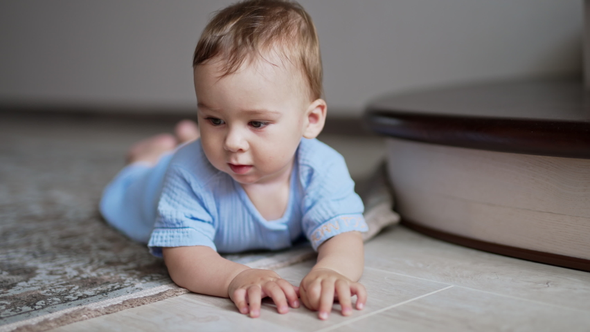 Nice cute child lies on the floor watching the ball rolling in front of him. Little boy crawling up to the toy watching it move. Close up. | Shutterstock HD Video #1093368889