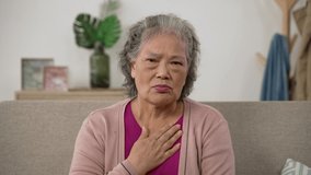 worried Korean mature grandma patient keeping hand on chest while talking to webcam having consultation with doctor via conferencing technology at home