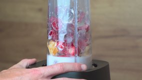 Slow motion video of blender mixing milk, ice and fruits for smoothie