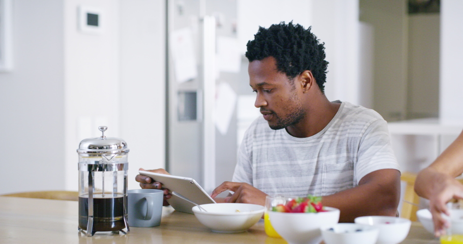 Happy, loving and caring couple kiss while eating breakfast at home on the weekend. Young african american attractive female enjoying a meal and bonding with her boyfriend at home in the kitchen | Shutterstock HD Video #1093375103