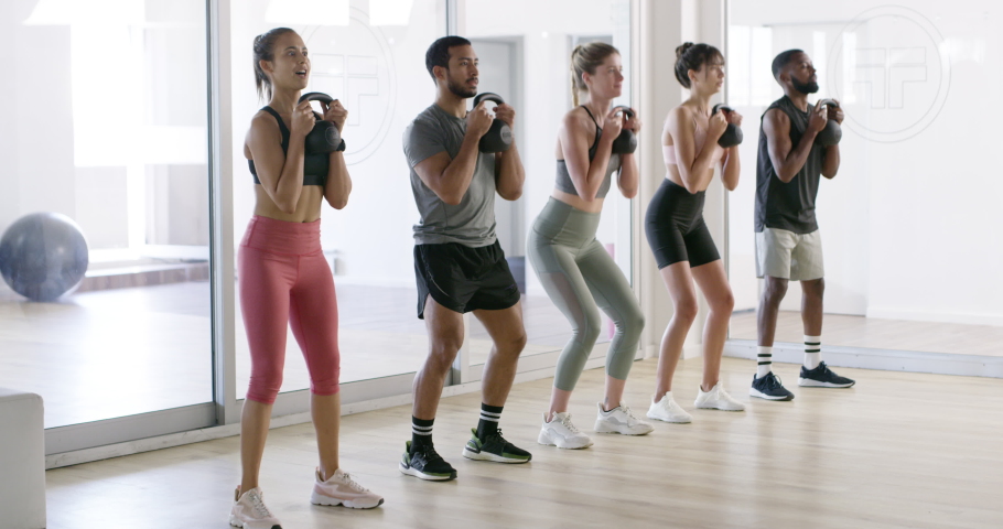 Fit, active or healthy people squatting with kettlebell weights in gym workout, exercise or training class. Diverse group of friends lifting for cardio health, stamina or endurance or building Royalty-Free Stock Footage #1093375143