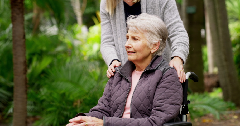 Love, bonding and hugging with a young woman visiting her senior, disabled and happy mother in a wheelchair. Mature female and her adult daughter spending time together as a family in the garden | Shutterstock HD Video #1093375255