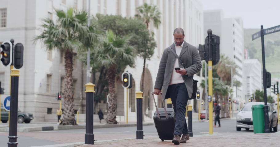 Traveling businessman carrying suitcase and phone on business travel, walking or commuting to airport in modern city street. Texting corporate professional with luggage, suitcase or baggage overseas | Shutterstock HD Video #1093375325