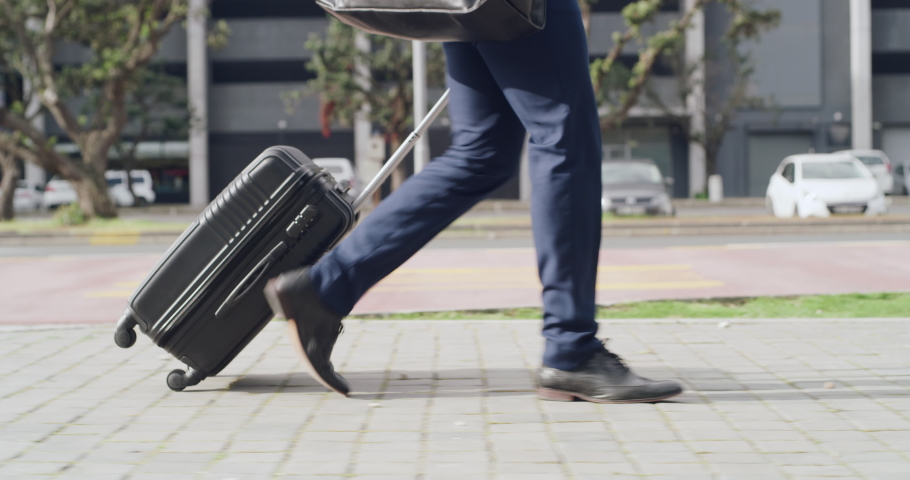 Corporate traveling businessman walking and carrying a suitcase in street of urban city town on his way to the airport. Modern executive employee on his way to catch business trip flight with | Shutterstock HD Video #1093375335