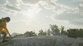 The girl climbs the rocks to the top of the mountain and raises her hands uphill. The feeling of victory and freedom above the clouds in a beautiful mountain landscape. High quality 4k footage