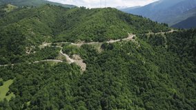 mountain winding serpentine road in a gorge between green mountains under a clear sky and white clouds in summer