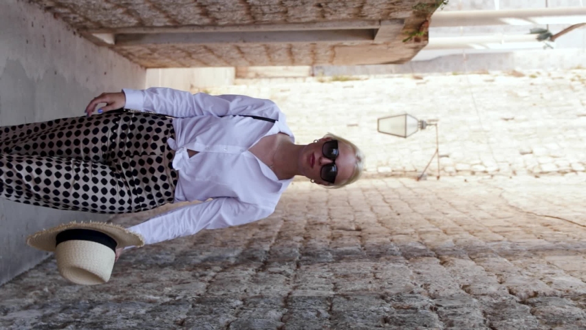 Happy young girl wearing a straw hat walks down the narrow streets of Dubrovnik