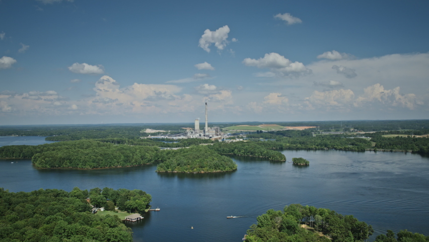 Wide aerial hyperlapse with power plant centered in frame and boats on the water in the foreground at Hyco Lake, North Carolina.